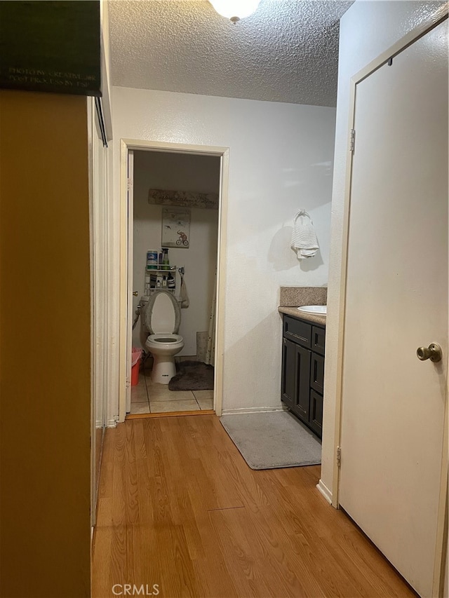 hall with light hardwood / wood-style floors, sink, and a textured ceiling