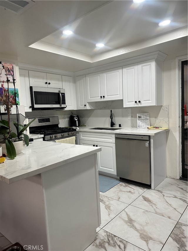 kitchen with a raised ceiling, sink, kitchen peninsula, white cabinetry, and stainless steel appliances