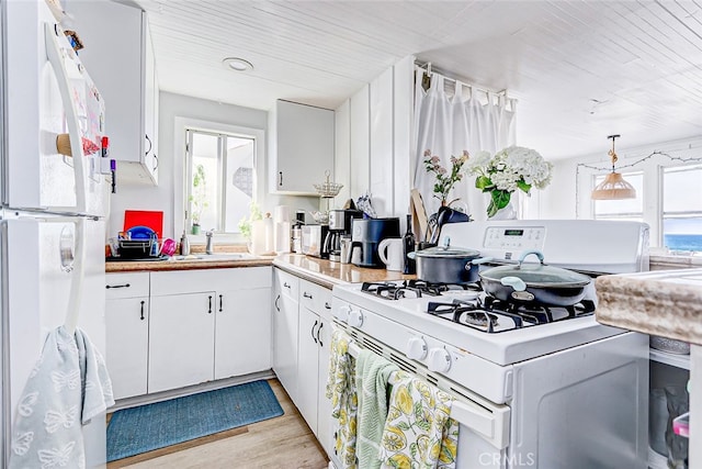 kitchen featuring white appliances, white cabinets, light hardwood / wood-style flooring, and a wealth of natural light