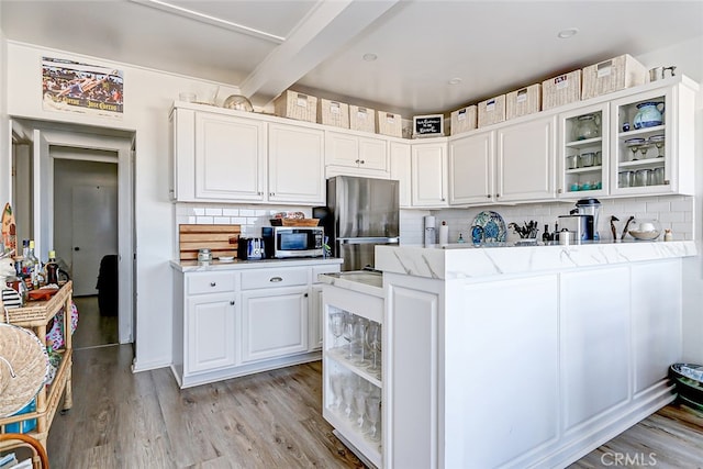 kitchen with white cabinets, appliances with stainless steel finishes, light hardwood / wood-style floors, and tasteful backsplash