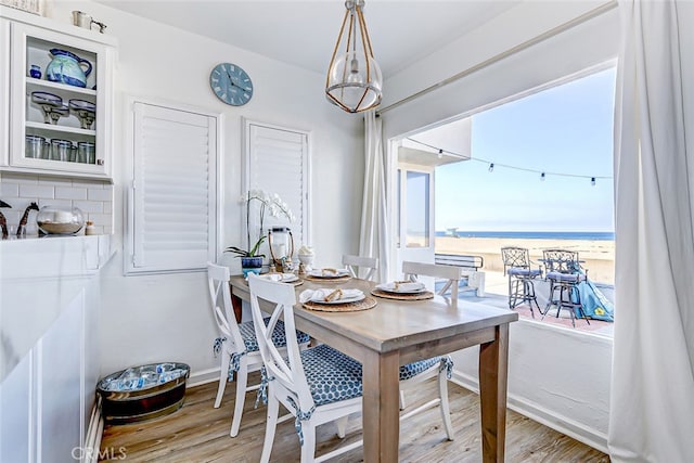 dining room featuring a water view, plenty of natural light, and light hardwood / wood-style flooring