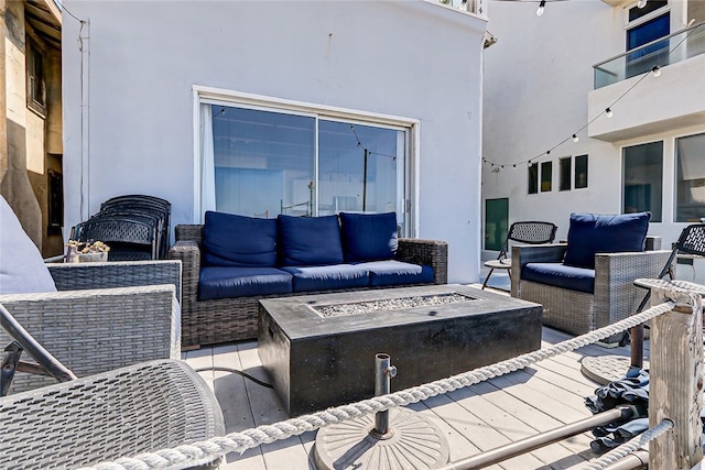 view of patio / terrace with a balcony and an outdoor living space with a fire pit