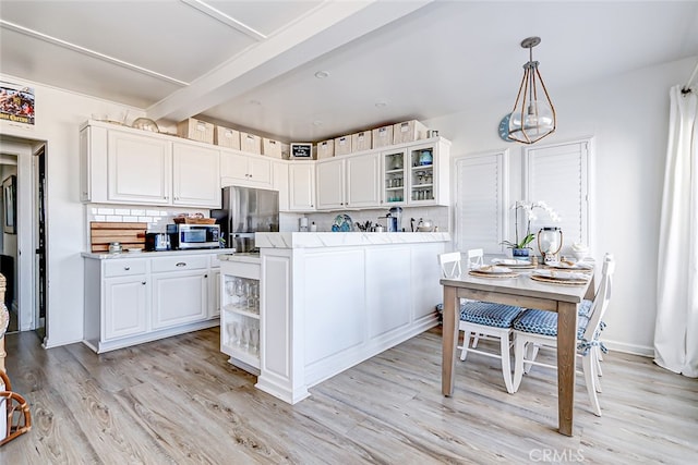 kitchen with pendant lighting, light hardwood / wood-style flooring, white cabinetry, appliances with stainless steel finishes, and decorative backsplash