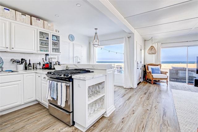 kitchen with kitchen peninsula, light wood-type flooring, stainless steel range with gas stovetop, and white cabinets