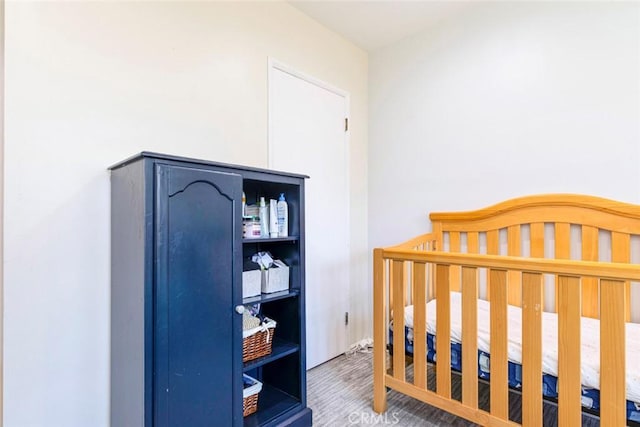 bedroom featuring wood-type flooring and a crib