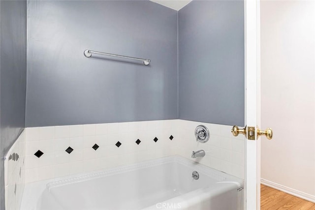 bathroom with wood-type flooring and a tub to relax in