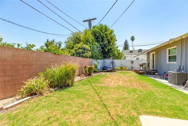 view of yard with central AC, a deck, and a trampoline