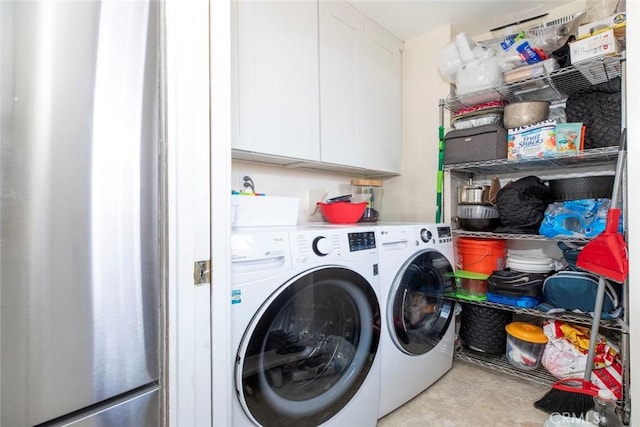 clothes washing area featuring washer and clothes dryer and cabinets