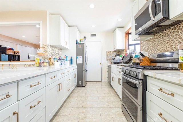 kitchen featuring white cabinets, appliances with stainless steel finishes, and tasteful backsplash