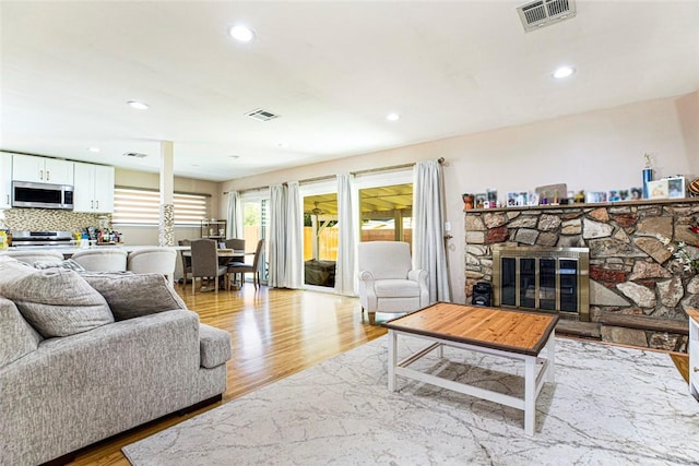 living room featuring light hardwood / wood-style flooring and a stone fireplace