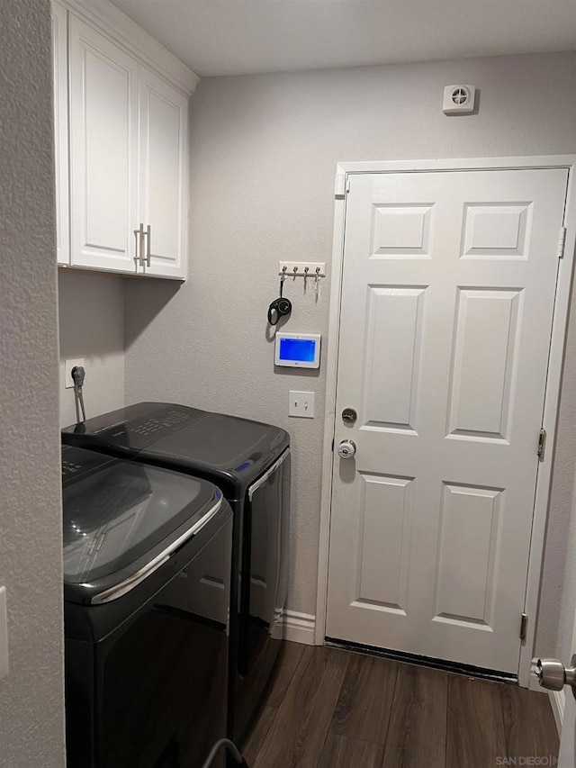 clothes washing area featuring cabinets, dark hardwood / wood-style flooring, and washing machine and clothes dryer