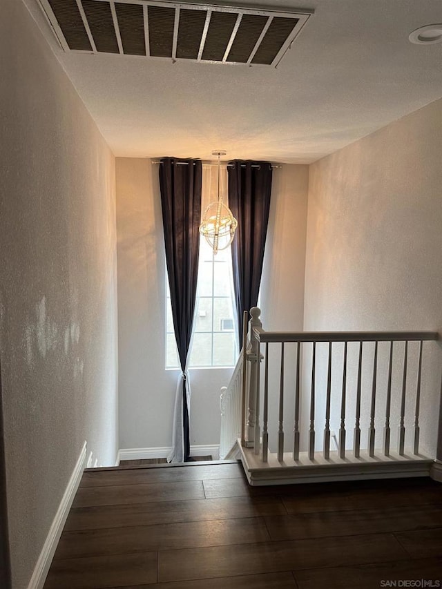 stairway featuring wood-type flooring and an inviting chandelier