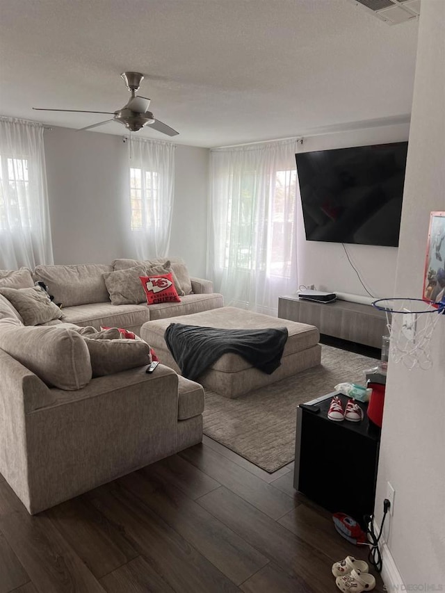 living room featuring ceiling fan, a healthy amount of sunlight, and dark wood-type flooring