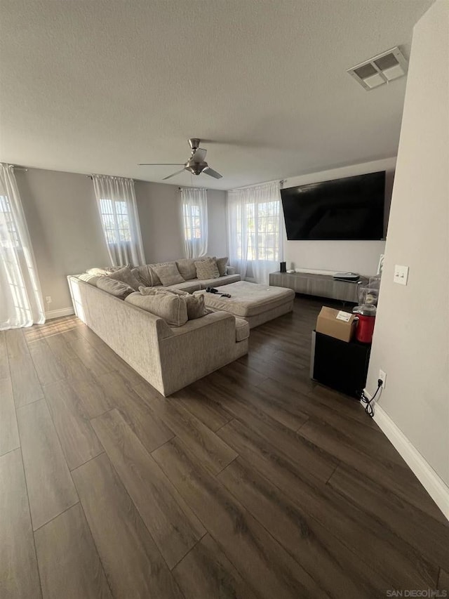 unfurnished living room with dark wood-type flooring, ceiling fan, and a textured ceiling