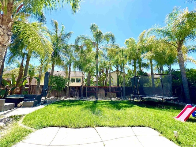 view of yard with a trampoline and a patio