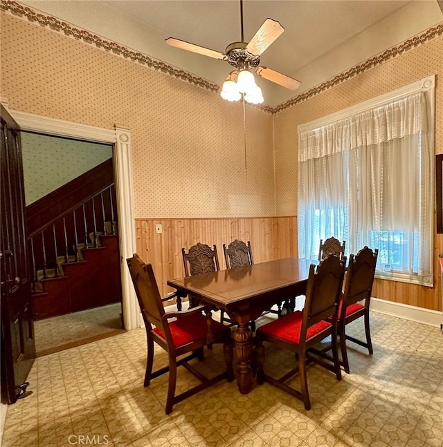 dining space featuring wooden walls and ceiling fan