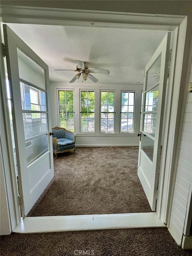 unfurnished sunroom featuring a healthy amount of sunlight and ceiling fan