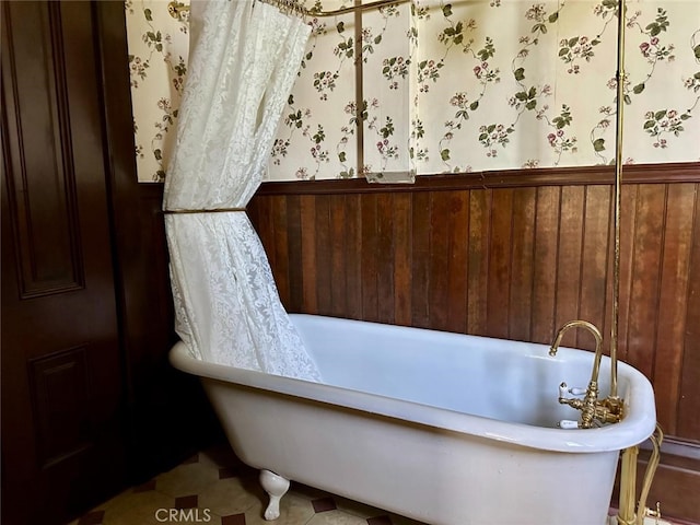 bathroom featuring a bath and wood walls