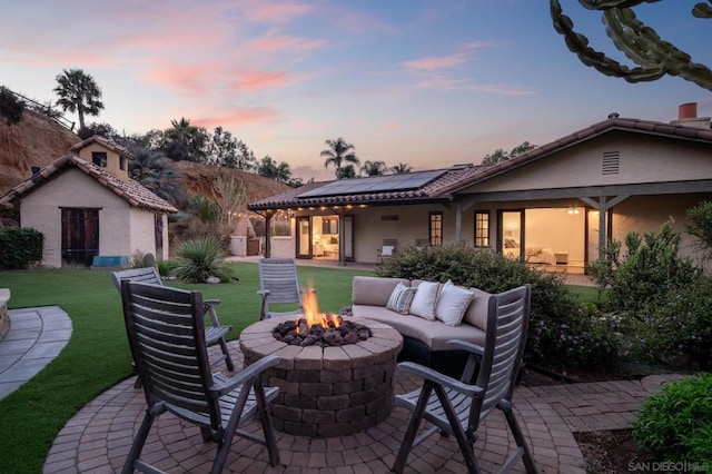 patio terrace at dusk featuring a yard and an outdoor living space with a fire pit