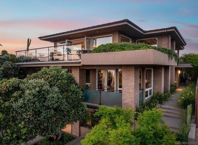 back house at dusk with a balcony