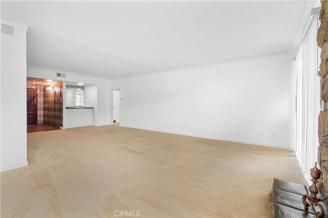 unfurnished living room featuring light carpet and baseboards