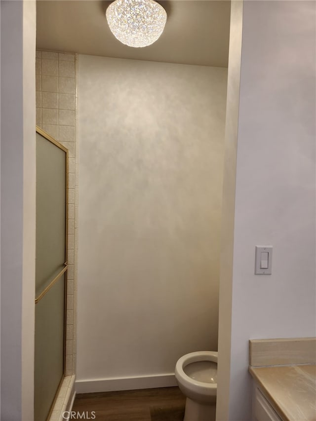 full bath featuring toilet, a shower stall, baseboards, and wood finished floors