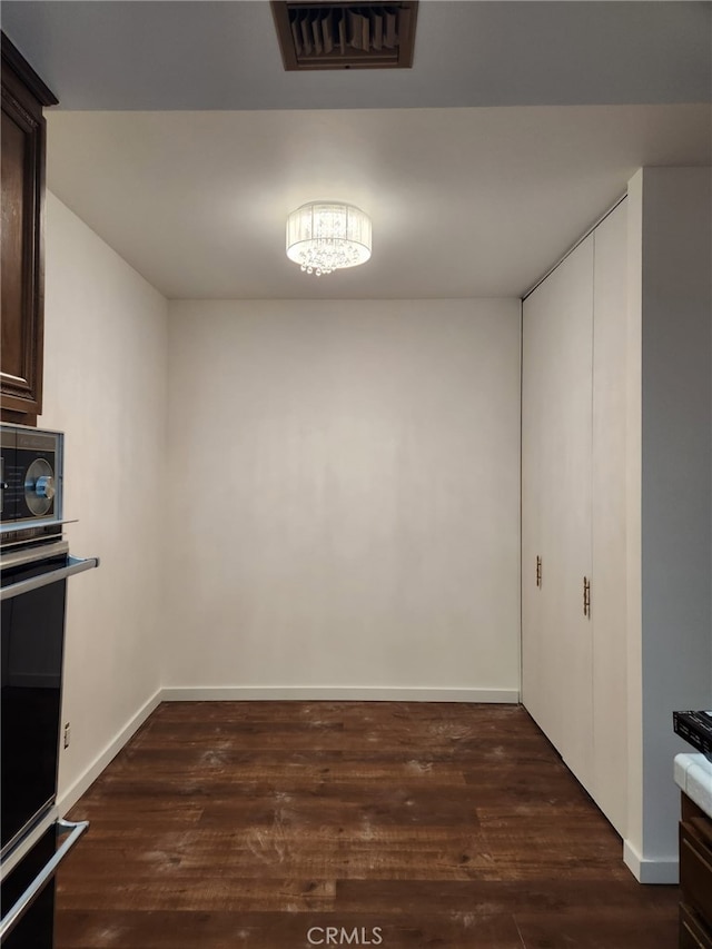 unfurnished dining area with baseboards, visible vents, and dark wood-type flooring