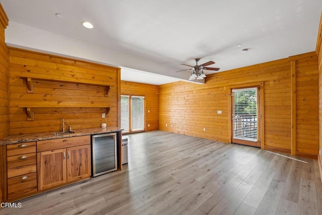 kitchen featuring plenty of natural light, beverage cooler, wood walls, and light stone countertops