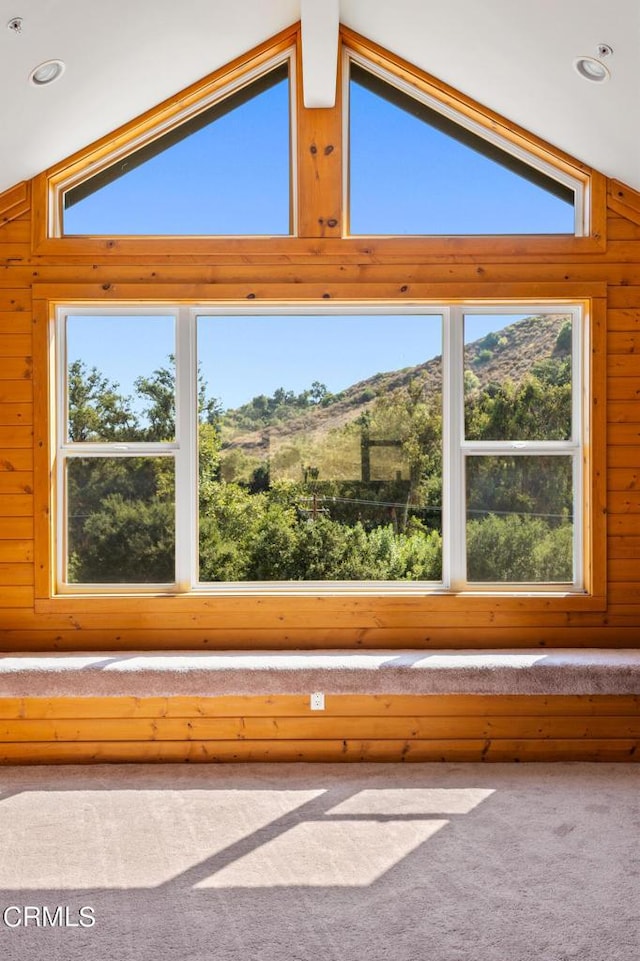 interior details featuring beam ceiling, a mountain view, wooden walls, and carpet flooring