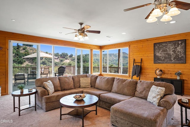 carpeted living room featuring ceiling fan and wooden walls