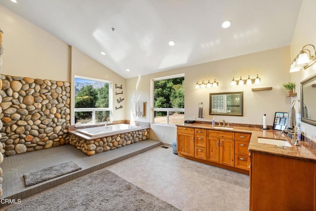 bathroom featuring tile patterned floors, vanity, lofted ceiling, and a tub to relax in