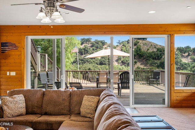 living room featuring ceiling fan, a wealth of natural light, and wood walls