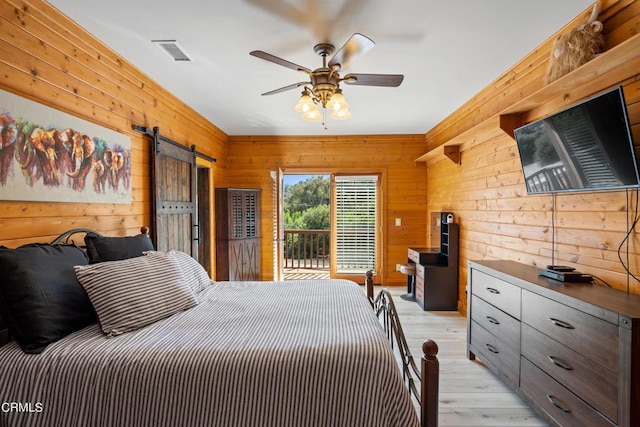 bedroom with wooden walls, ceiling fan, a barn door, and access to outside