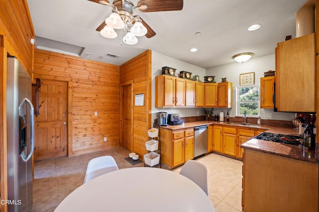 kitchen with appliances with stainless steel finishes, dark stone countertops, wooden walls, and sink