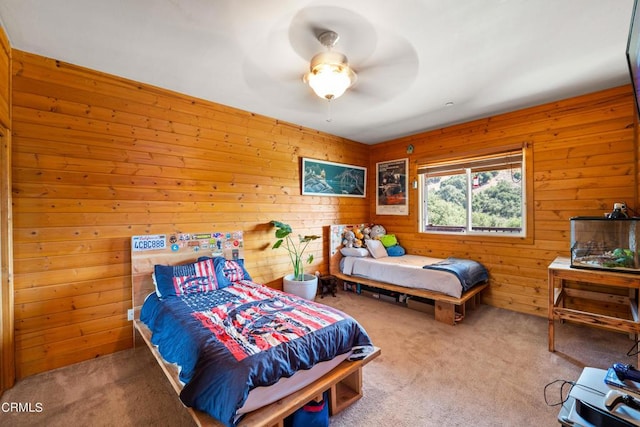 carpeted bedroom with ceiling fan and wood walls