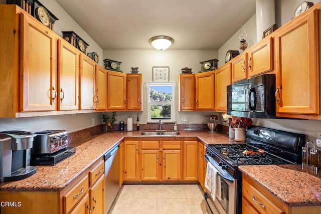 kitchen featuring light stone counters, sink, appliances with stainless steel finishes, and light tile patterned floors