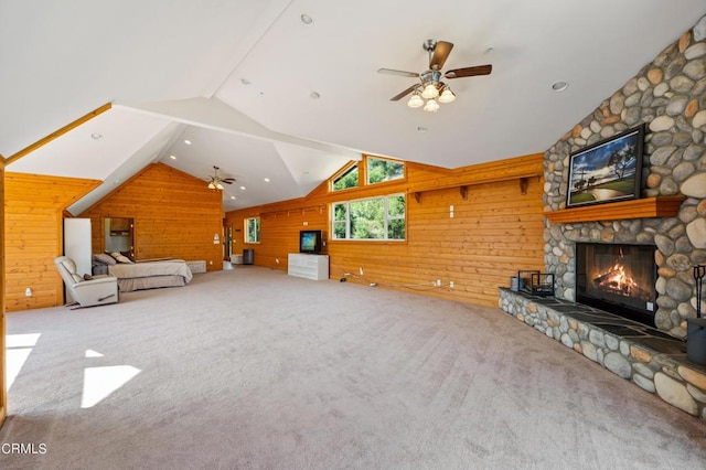 unfurnished living room featuring ceiling fan, carpet floors, vaulted ceiling, a fireplace, and wood walls