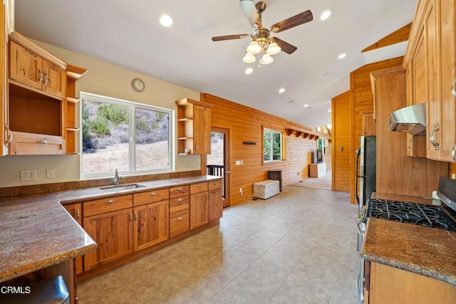 kitchen with extractor fan, wood walls, gas stove, fridge, and lofted ceiling