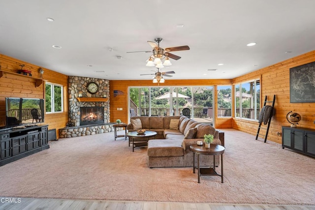 living room featuring ceiling fan, plenty of natural light, and a stone fireplace