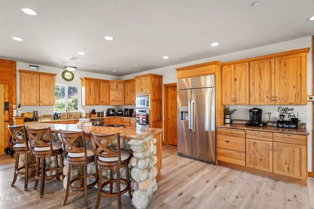 kitchen featuring light stone countertops, a center island, a breakfast bar, and built in appliances