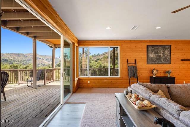 living room featuring a healthy amount of sunlight, a mountain view, and wooden walls