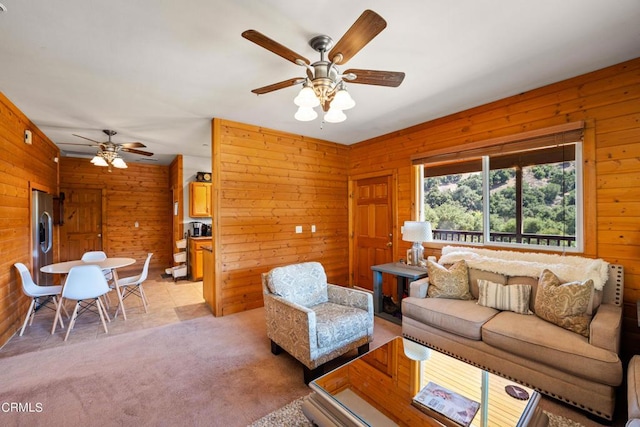 carpeted living room with ceiling fan and wood walls