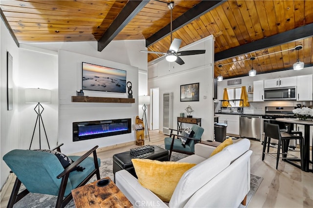 living room with wood ceiling, light hardwood / wood-style floors, vaulted ceiling with beams, a large fireplace, and ceiling fan