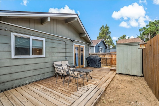 wooden terrace featuring a storage unit and a grill