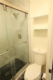 bathroom with toilet and a shower with door