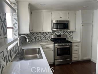 kitchen with sink, dark wood-type flooring, stainless steel appliances, decorative backsplash, and white cabinets