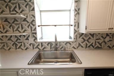 kitchen featuring white cabinets, dishwashing machine, decorative backsplash, and sink