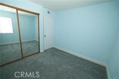 unfurnished bedroom featuring a closet and dark carpet