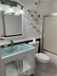 full bathroom with toilet, vanity, tile patterned floors, and bath / shower combo with glass door