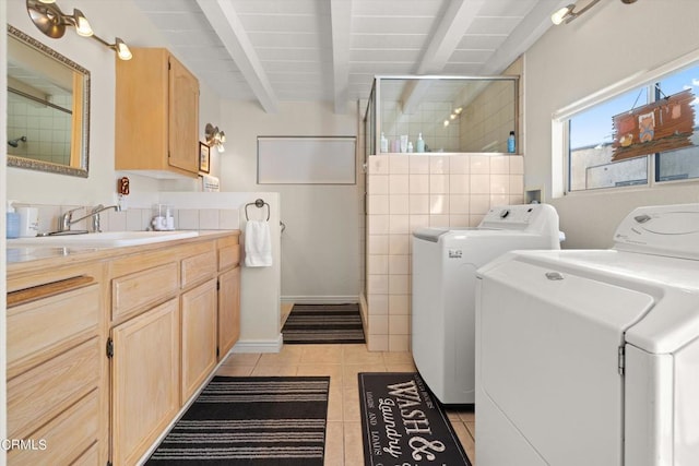 washroom featuring sink, light tile patterned floors, and washing machine and dryer